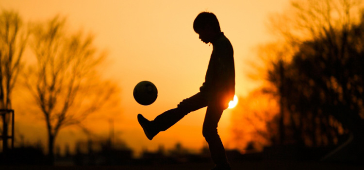 夕暮れにサッカーをする少年